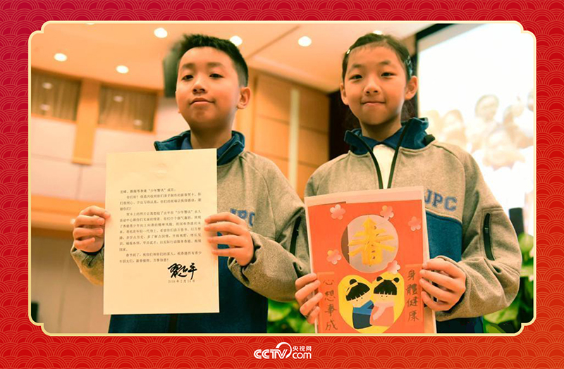 圖為香港“少年警訊”成員郭宏晞（左）展示習(xí)主席回信、羅顥凝（右）展示送給習(xí)主席的賀卡并合影。